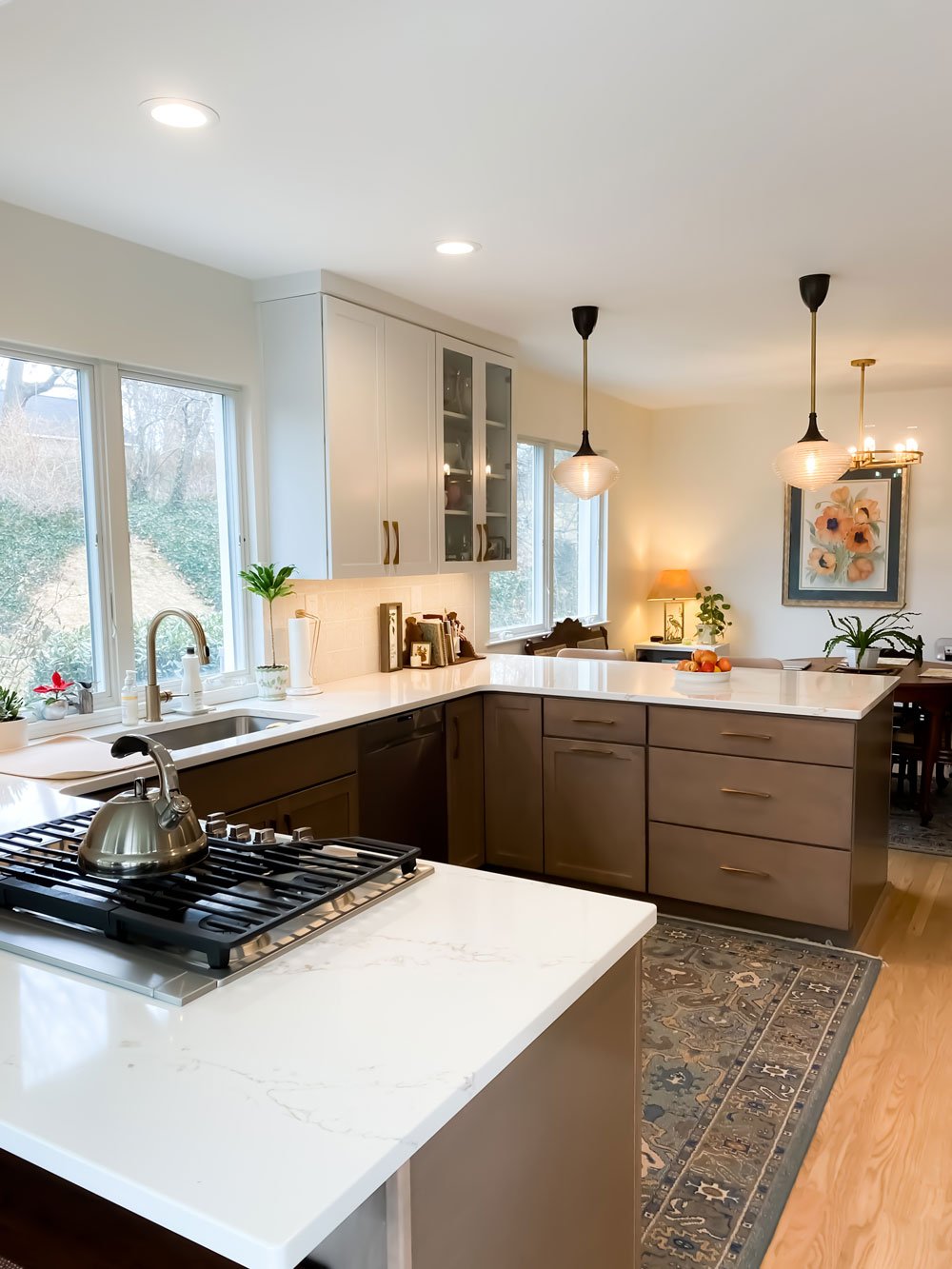 Contemporary kitchen with white polished stone countertops, black hanging lamps, and white wooden cabinets