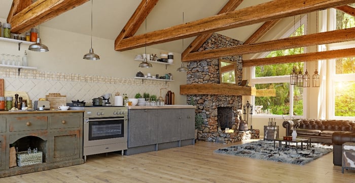 An open kitchen and family room with notable exposed wood beams and stone fireplace.