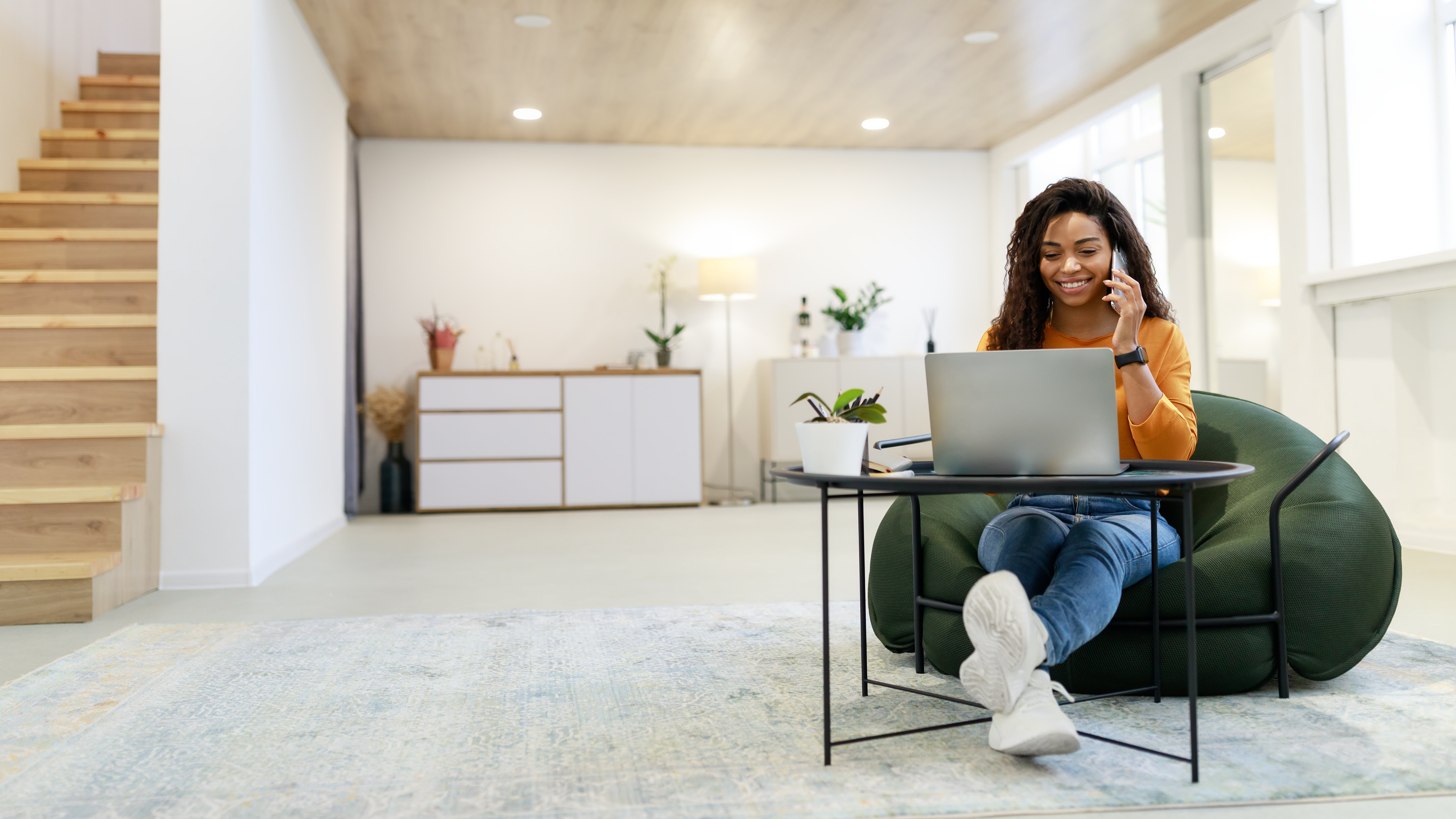 Young woman sitting at home working remotely and currently speaking on the phone