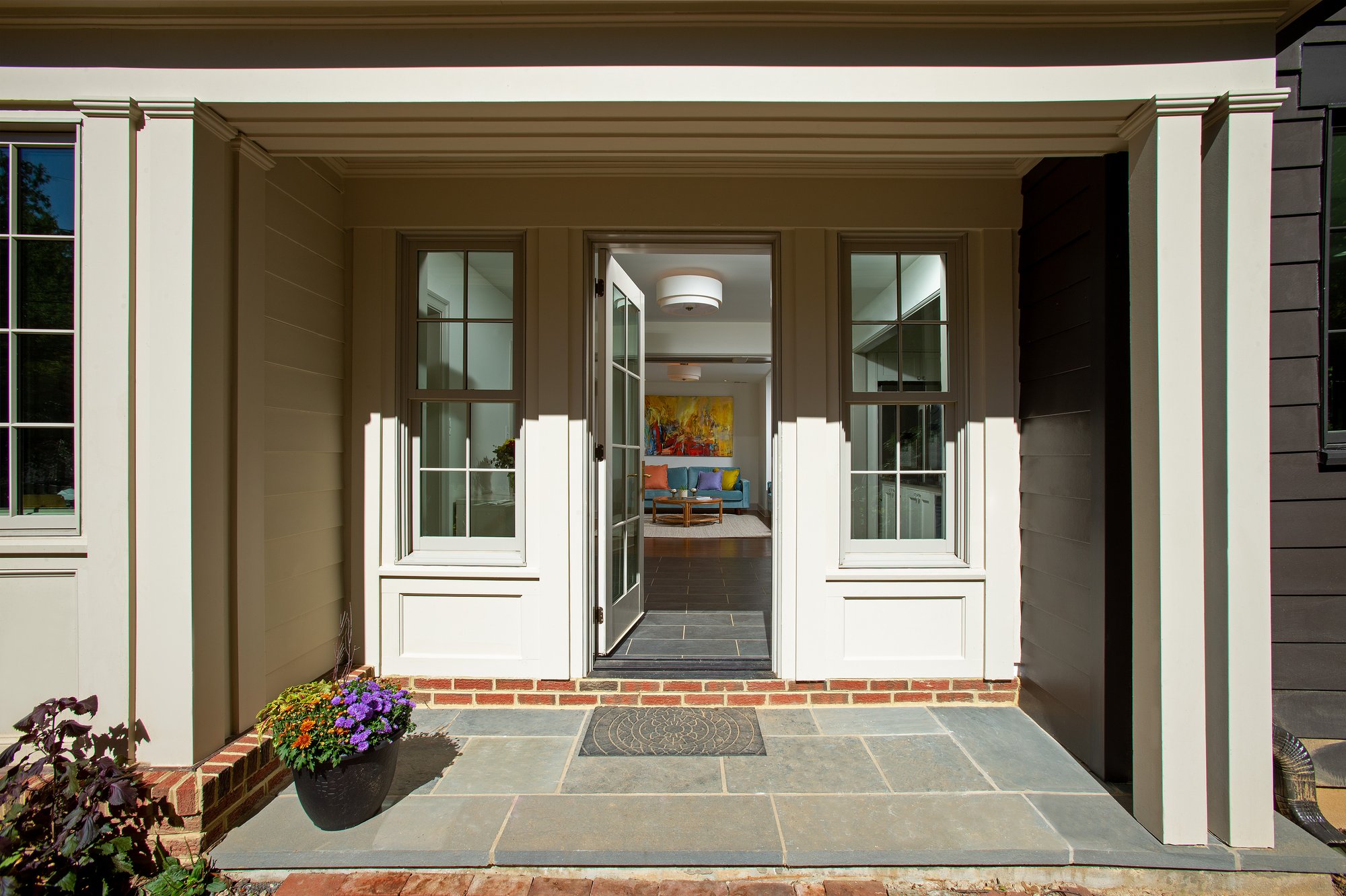 Front door and vestibule with two windows on each side of the front door and stone tile flooring