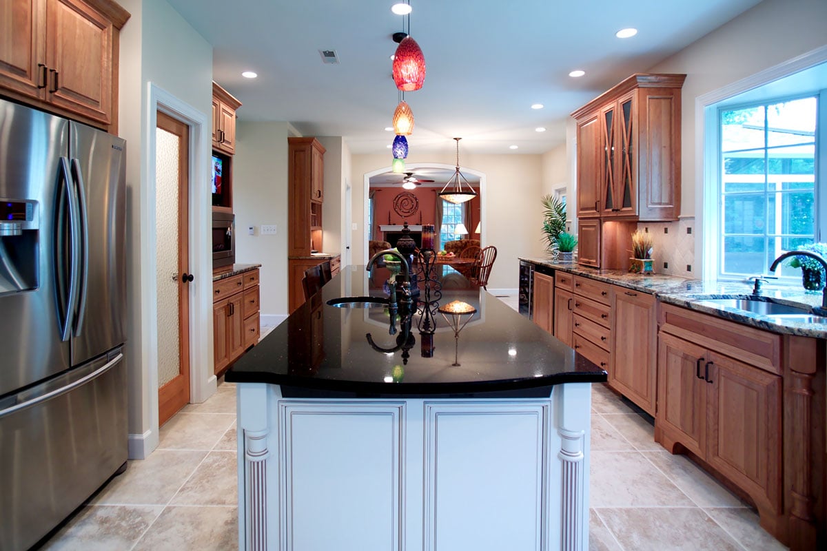 Large grey wooden island with black granite countertop overlooking a family dining table