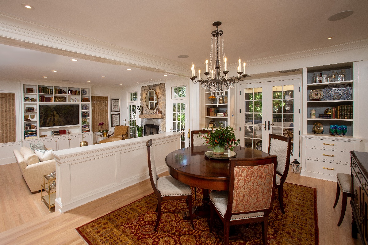 Family dining room with hanging metal chandelier, wooden kitchen table for four, and deep red and burgundy area rug