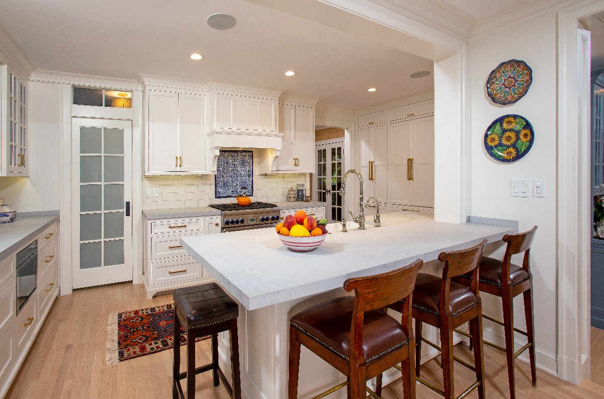 Kitchen island with grey natural stone counter and four cherry wood bar stools for seating and entertaining guests
