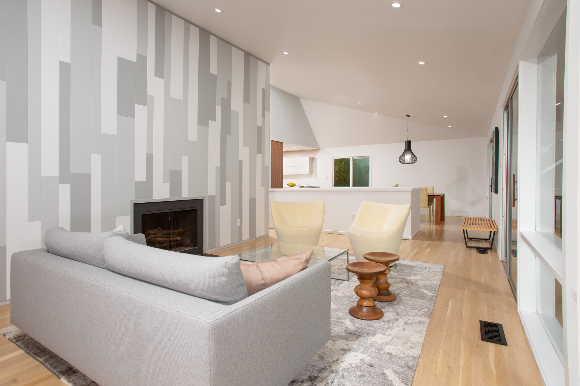 Cozy and contemporary living room with a grey loveseat and a glass coffee table. Abstract wallpaper on the left