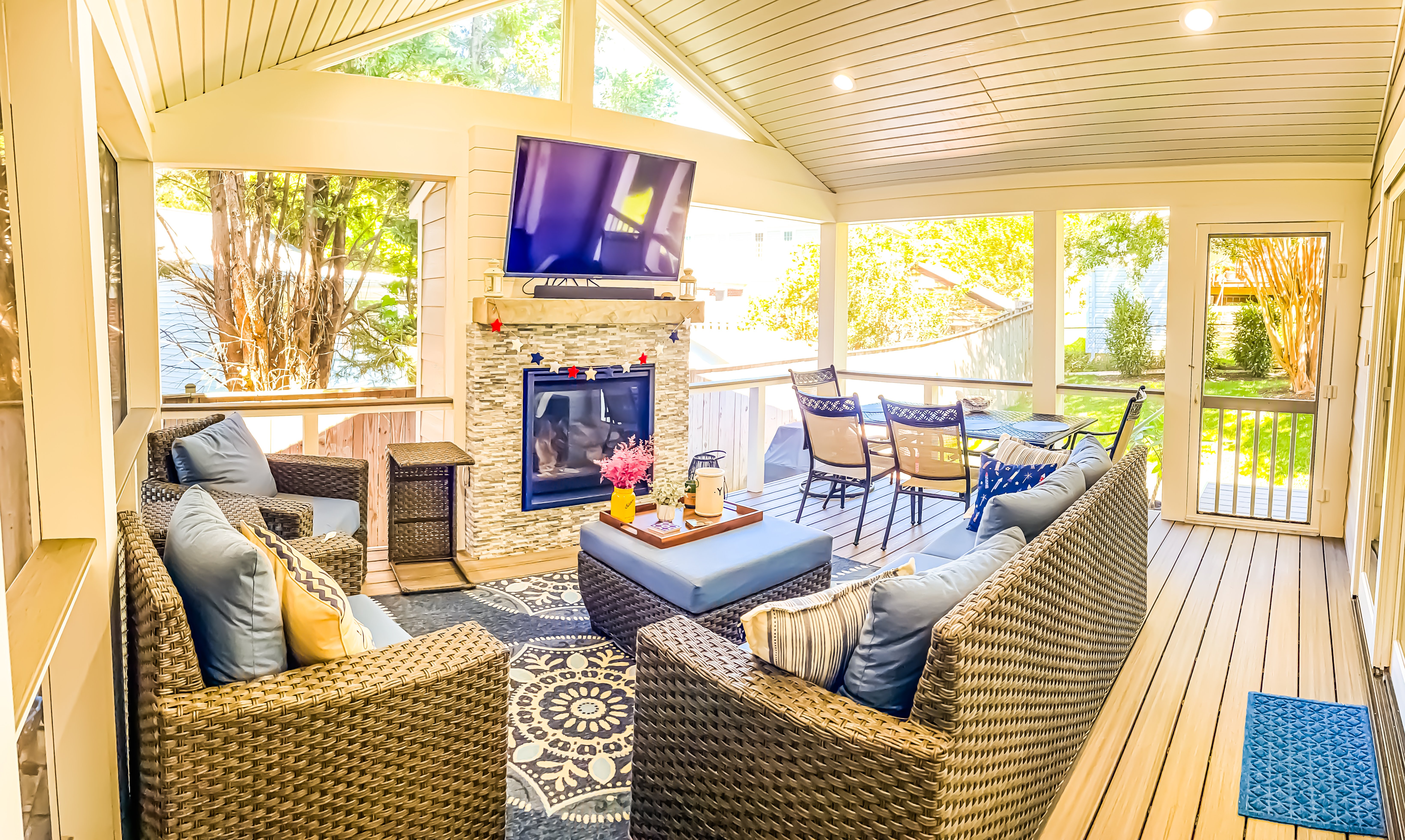 A screened in porch with couches, fireplace, and television.