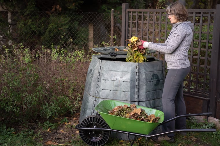 A women adding organic material to a compost bin.
