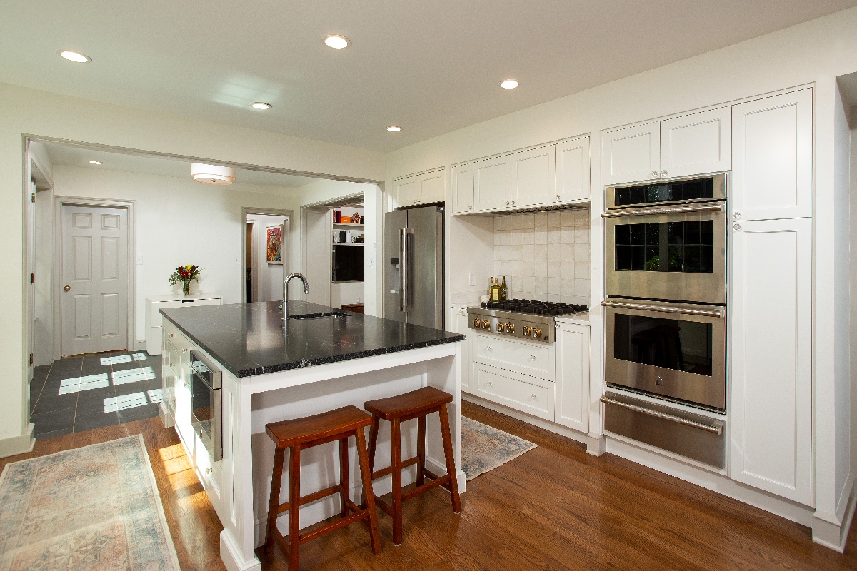 photo of a kitchen with white cabinetry, stone countertops and stainless steel appliances