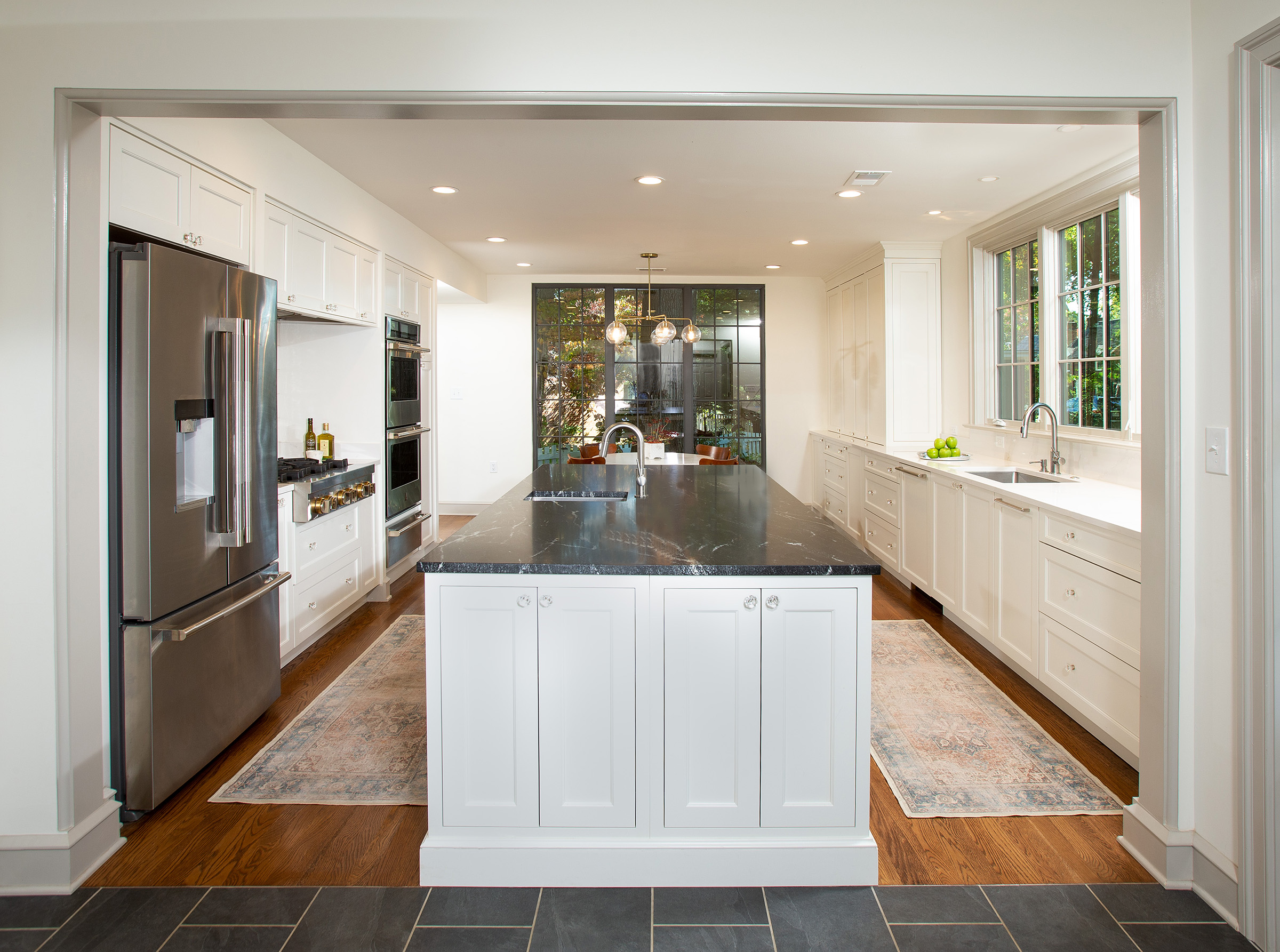 Photo of a kitchen with white cabinetry, stone countertops and stainless steel appliances