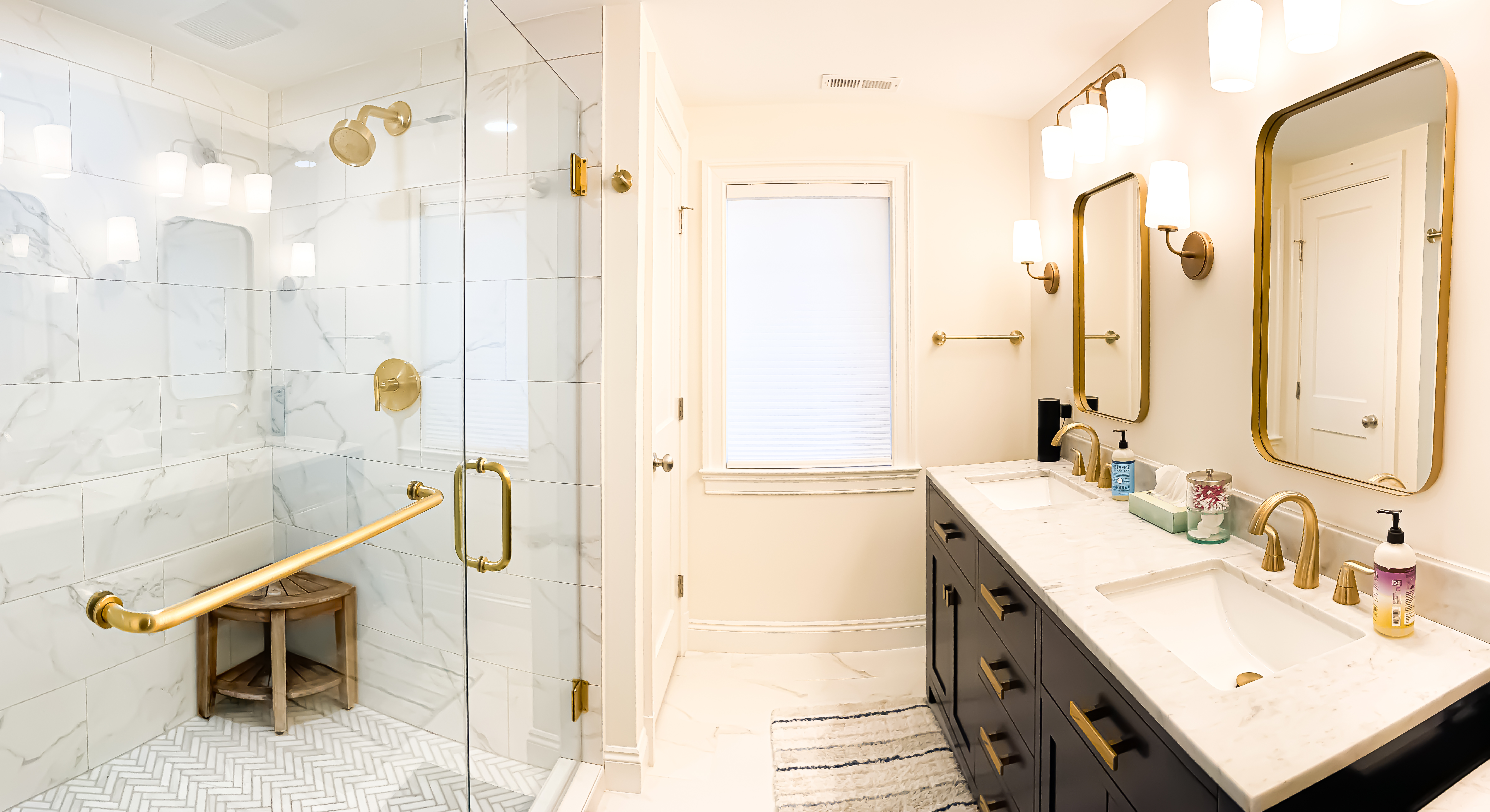 photo of a bathroom with a walk-in shower and vanity with double sinks, gold accents and beautiful tile